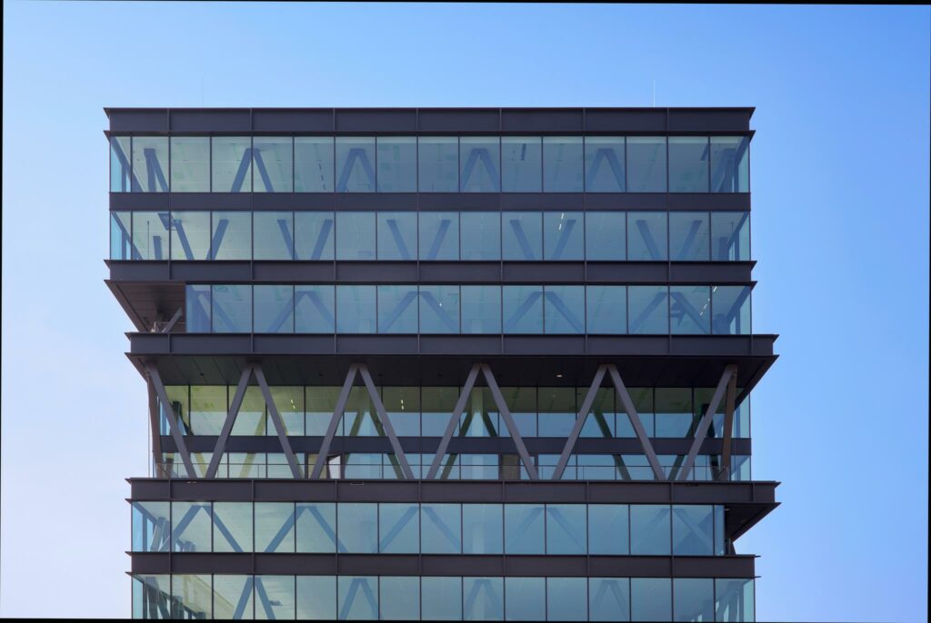 Modern glazen kantoorgebouw aan de Joan Muyskenweg met opvallende stalen X-structuren in de gevel.